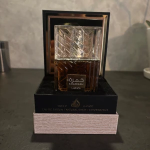 Lattafa Khamrah Eau de Parfum 100ml - Lattafa Khamrah är en lyxig parfym i en tung, fyrkantig glasflaska med mönstrad design och guldiga detaljer. Helt ny