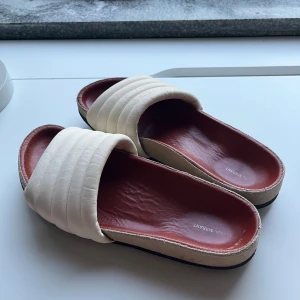 Tofflor / flipflops från Isabel Marant - Super coola Isabel Marant tofflor/flipflops med röd sula o beige över grej (?). Står ingen storlek men skulle säga passar 36/37. De är välskötta o så fina🥰❤️. Skriv om någon fråga! 