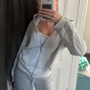 Grå hoodie med dragkedja - Mysig grå hoodie med dragkedja och huva. Jackan har en avslappnad passform, fickor framtill och ribbade muddar vid ärmslut och nederkant. Perfekt för chill dagar eller när du vill ha en enkel och stilren look💗