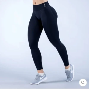 Svarta Impact Leggings från DFYNE - Snygga svarta Impact Leggings från DFYNE i stretchigt material med hög midja. Perfekta för träning eller chill, sitter tight och formar kroppen. Tillverkade i 90% nylon och 10% elastan för maximal komfort och rörelsefrihet. Diskret logga vid linningen. Byxorna har en scrunch på rumpan för formationen. De är använda endast en gång, och säljer dem då jag föredrar leggings utan scrunch.