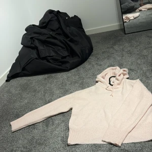 Ljusrosa stickad hoodie från Gina Tricot - Supermjuk och mysig ljusrosa stickad hoodie från Gina Tricot. Tröjan har huva med snörning, ribbade muddar och är långärmad. Perfekt för dig som gillar en chill och enkel stil med en touch av söt pastell.