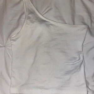 Vit one shoulder topp  - Säljer en vit ribbad one shoulder topp från Gina Tricot i storlek XXS. Toppen är ärmlös och har en tight passform 