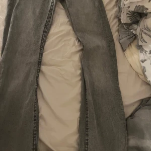 Grå jeans med fickdetaljer - Säljer ett par grå jeans med snygg tvätt och coola fickdetaljer både fram och bak. Byxorna är bootcut och klassisk femficksdesign med extra lock på bakfickorna. Perfekta för dig som gillar en avslappnad men ändå stilren look. 