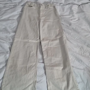 Beiga jeans - Snygga beiga, högmidjade jeans från Lindex i modell Viola. Byxorna har raka, vida ben och klassisk femficksdesign. Tillverkade i bomull med en mjuk känsla och knappstängning framtill. Perfekta för en chill och stilren look. Använt ett fåtal gånger, finns vissa fläckar men inget som syns mycket! Köp direkt i app! Är snäppet mörkare än på bilderna. Nypris runt 200 kr.