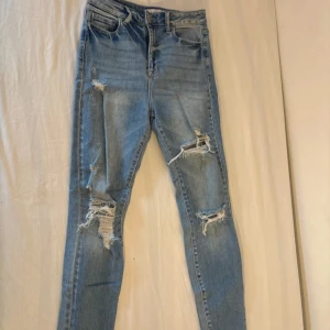Ljusblå ripped skinny jeans från Cello - Säljer ett par ljusblå skinny jeans från Cello med slitna detaljer och hål på båda benen. Jeansen har klassisk femficksdesign, är tillverkade i stretchigt denim för en tight passform. Perfekta för en avslappnad och trendig look.
