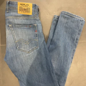 Replay Grover straight fit jeans blå  - Snygga Replay Grover jeans i klassisk blå tvätt med raka ben och straight fit. Jeansen har fem fickor, ljusa slitningar och coola detaljer på bakfickorna. Perfekta för dig som gillar en tidlös och avslappnad look. Storlek 28/30