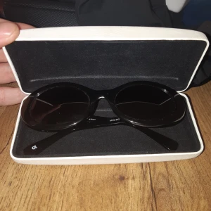 Svarta ovala solglasögon Versace - Säljer ett par svarta ovala solglasögon från Versace, modell 342. Glasögonen har klassisk svart båge i blank plast och silverfärgade Medusa-detaljer på sidorna. Kommer i originalfodral med Versace-logga. Riktigt snygga och ikoniska solbrillor.