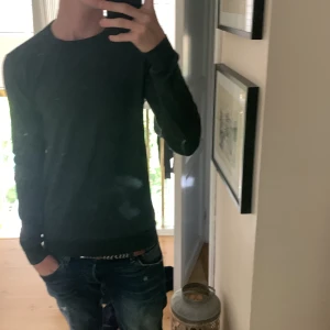 Mörkgrön stickad tröja Samsøe Samsøe - Snygg mörkgrön stickad tröja från Samsøe Samsøe. Enkel design med rund halsringning och långa ärmar. Perfekt för dig som gillar stilrena och bekväma plagg. Passar till jeans eller chinos för en clean look.