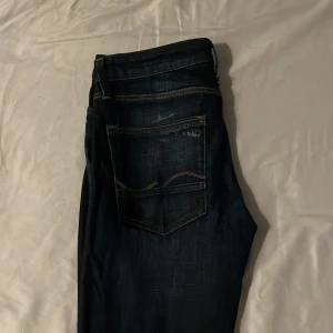 Mörkblå jeans från Jack & Jones - Riktigt snygga mörkblå jeans från Jack & Jones med klassisk femficksdesign. Jeansen har rak/slim passform. 30/32 men kan passa 34