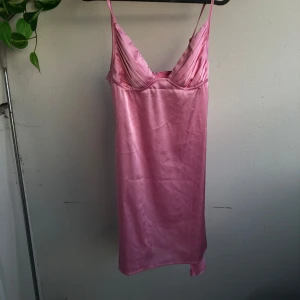 Rosa satin  klänning - Snygg rosa kortklänning i satin med smala axelband som går att justera och v-ringad urringning. Liten dragkedja ibak.