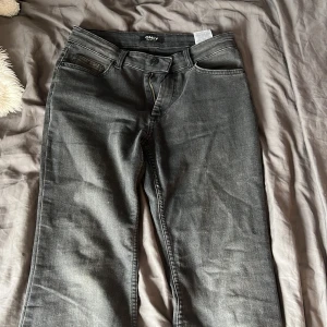 Gråa wide jeans från ONLY - Snygga gråa jeans från ONLY med breda ben och klassisk femficksdesign. Jeansen har en normalhög midja, dragkedja och knapp framtill samt bälteshällor. Perfekta för dig som gillar en avslappnad och trendig stil.
