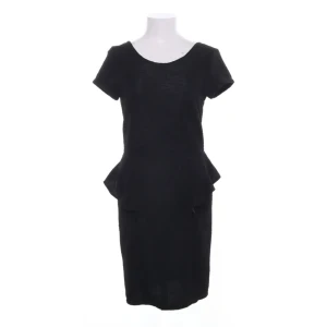 Svart peplumklänning med textur - Snygg svart kortklänning med peplumdetalj i tyg med textur. Klänningen har rund halsringning och dragkedja i ryggen. Perfekt för dig som gillar en stilren och feminin look. Den följer former men visar inte för mycket eftersom tyget har lite textur.