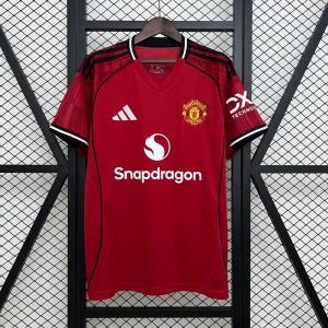 25/26 MANCHESTER UNITED  - Röd Manchester United fotbollströja från Adidas med klubbmärke på bröstet, vita och svarta detaljer på krage och ärmslut samt svarta Adidas-ränder på axlarna. V-ringad hals och tryckta sponsorer på framsidan. Tillverkad i lätt och ventilerande polyester. Leverans 5-20 dagar.