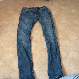 Blå jeans från Tiger of Sweden - Snygga blå jeans från Tiger of Sweden med klassisk femficksdesign och kontrastsömmar. Jeansen har normal passform och raka ben, tillverkade i slitstarkt bomullsjeans. Perfekta för dig som gillar stilrena och tidlösa jeans.