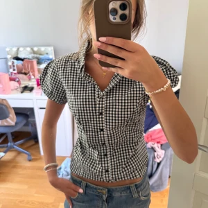 Rutig kortärmad skjorta från KappAhl - Supersöt svartvit rutig skjorta från KappAhl med puffiga korta ärmar och klassisk krage. 