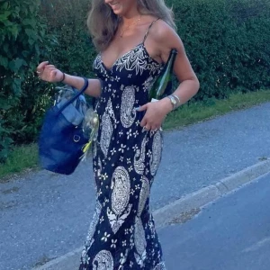 Svartvit långklänning med paisleymönster - Säljer en svart långklänning med tunna axelband och vit paisleyinspirerat mönster. Klänningen har djup v-ringning och är figurnära upptill men med bra stretch så skulle säga att den passar både XS-S. Sjukt skönt material nu under varma sommardagar! Går ner till fötterna på mig som är 163cm🥰  