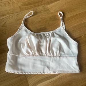 Ljusrosa linnetopp med smockrygg - Supersöt ljusrosa linnetopp med tunna axelband och rynkade detaljer framtill. Baksidan har smock för extra stretch och passform. Perfekt till sommarens outfits och enkel att matcha med jeans eller kjol. XS-S