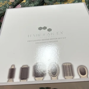 Hair Lab EX Pro Salong Brush Dryer Set - Pro Salong Brush Dryer Set 2.0 Exclusive Edition från Hair Lab EX. Setet innehåller flera utbytbara borstar i beige och svart, perfekt för styling och föning. Ergonomiskt handtag och olika borsthuvuden för volym, rakt eller vågigt hår. Snygg och praktisk design.