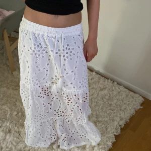 Vit långkjol med broderade detaljer Amisu - Superfin vit långkjol från Amisu med broderade hålmönster och volangkant. Kjolen har resår i midjan med snörning och tofsar för en chill och somrig vibe. Helt ny och aldrig använd. Nypris 369 kr