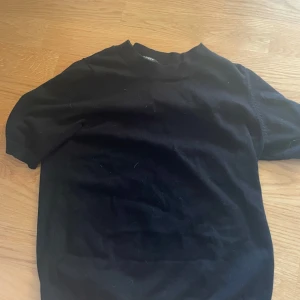 Svart stickad t-shirt - En svart stickad t-shirt med rund hals och korta ärmar. Enkel och stilren modell som passar till det mesta. T-shirten är i mjukt material och har en normal passform.