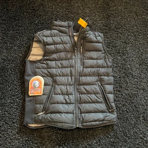  Parajumpers väst xs - Säljer en snygg svart dunväst från Parajumpers i mycket bra skick. Västen har en dragkedja framtill och är perfekt för höst och vår. Den är quiltad och har en normal passform. Märkets logga syns tydligt på bröstet och nacken. Perfekt för lager-på-lager-stil!