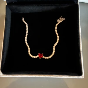 Pandora armband med röd sten - Snyggt armband från Pandora i silverfärg med glittrande stenar längs hela bandet och en röd hjärtformad sten i mitten. Perfekt accessoar för att ge din outfit lite extra bling. Levereras i originalask från Pandora.