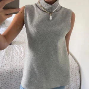 Zara stickad polotröja - Säljer en stilren grå stickad polotröja med hög polokrage från Zara. Storlek M. Västen är ärmlös och har en rak, något loose passform. Perfekt att styla över en skjorta eller t-shirt för en trendig lager-på-lager-look. Först bild är inte min bild, jag ville visa hur den ser ut på kroppen. Använd bara en gång, som ny. 