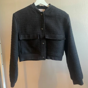 Svart cardigan jacka från Nelly - Snygg svart cardigan jacka från Nelly med croppad passform och stora fickor framtill. Endast använd 3-4 gånger så i mycket bra skick.