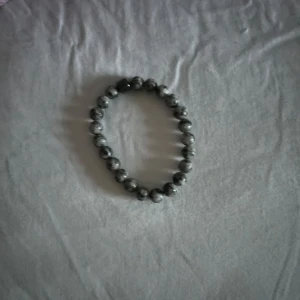 Grått pärlarmband med stenar - Snyggt armband med runda grå pärlor av sten, trädd på elastisk tråd. Perfekt accessoar för att ge din outfit en cool och stilren touch. Passar både till jeans och mer dressade looks.