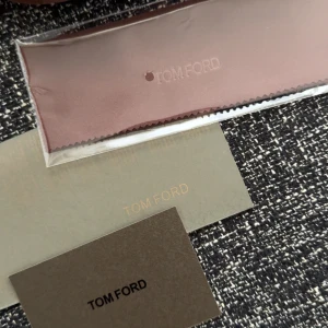 Svarta solglasögon från Tom Ford - Stilrena svarta solglasögon från Tom Ford med rektangulär form och diskreta gulddetaljer vid skalmarna. Snygg och modern design med robust båge i plast. Kommer med originalfodral, putsduk och certifikat.