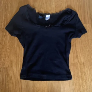 square neck topp med rosett  - Toppen är kort och stretchig, den har en fin square neckline och en liten rosett på framsidan, samt spets runt neckline. Pris kan diskuteras. Jag har använt toppen några gånger, men den har inga permanenta eller synliga defekter. 