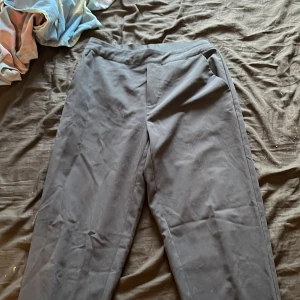 Blåa kostymbyxor från Object, stl 36 - Blåa kostymbyxor från Object i storlek 36. Byxorna har rak passform, resår i midjan baktill och sidfickor. Snygg minimalistisk look som funkar till många olika outfits. Materialet känns mjukt och lätt, perfekt för en clean stil.