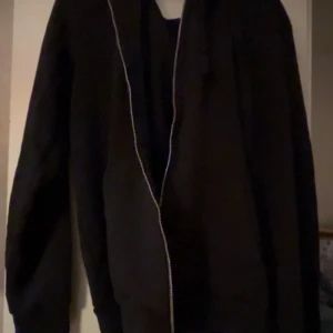 Mörkblå hoodiejacka med dragkedja - Mörkblå hoodiejacka med hel dragkedja framtill och huva. Jackan har en enkel och clean design, perfekt för en chill och avslappnad stil. Långärmad och i mjukt material som känns skönt mot huden.
