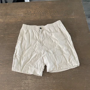 Linneshorts från H&M - Beiga linneshorts från H&M i regular fit. Dragkedja och knapp för gylfen