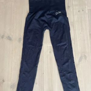 Svarta leggings från Drop of Mindfulness - Snygga svarta leggings från Drop of Mindfulness med hög midja och diskret logga framtill. De är tighta och stretchiga, perfekta för träning eller chill. Materialet är mjukt och följsamt, vilket gör dem riktigt bekväma att ha på sig. Passar M/L