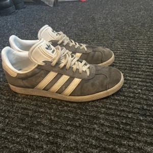 Grå Adidas Gazelle sneakers - Riktigt feta adidas gazelle skor i storlek 41,5. Skick 8/10 använda i ungefär 6 månader. Nypris ca 1200kr priset är diskuterbart
