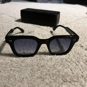 Svarta solglasögon från Chimi - Snygga svarta solglasögon från Chimi, modell LAB 04. De har en fyrkantig form med mörka linser och små silverdetaljer på bågarna. Perfekta för en stilren look. Använda någon gång, i perfekt skick!