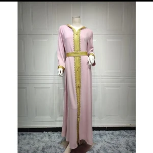 Rosa långklänning med gulddetaljer - Elegant rosa långklänning med vackra gulddetaljer längs framkanten och ärmsluten. Klänningen har långa ärmar och en rak passform som ger en sofistikerad look. Perfekt för speciella tillfällen.