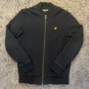 Svart zip sweatshirt från Lyle & Scott. STORLEK S - STORLEK S. En snygg svart zip sweatshirt från lyle Scott. Har ingen luva. Har använt den förr och folk runt mig har älskat den. Tyvärr så har den blivit för liten för mig. Bekväm och en dragkedja över hela bröstet. Priset kan diskuteras