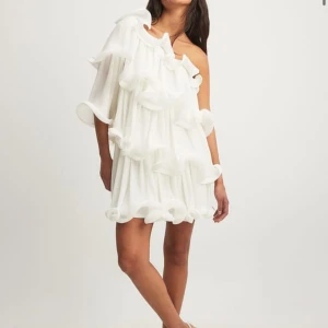 Vit volangklänning Nakd x Lojsan  - Säljer en super fin oneshoulder klänning från NAKD i storlek 34 men passar mig som vanligtvis har 34/36, jag är runt 170 cm lång  🥰Den är helt oanvänd med prislapp kvar från Lojsan wallins kollektion🤩säljer då den inte kommer till användning❤️obs helt slutsåld på hemsidan❤️