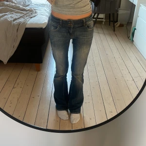 Blå bootcut jeans från Bershka - Säljer ett par klassiska blå bootcut jeans med låg midja. Jeansen har en snygg tvätt och femficksdesign. Perfekta för en avslappnad stil.
