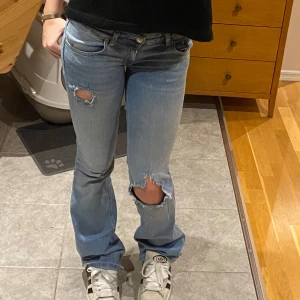 Ljusa low Waits jeans med slitningar - Säljer ett par ljusa jeans med coola slitningar på knäna. De har en klassisk femficksdesign och en knappgylf. Perfekta för en avslappnad stil. Storlek S 25/26, pris kan diskuteras, hör av er vid funderingar 