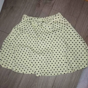 Gul prickig kjol - Fin kjol med shorts som använts till konståkning. Den har tyvärr färgat av sig lite grönt och har svart tusch på sig men man kan gömma det med banden på kjolen. Annars är kjol i bra skick. Kjolen har väldigt mycket strech i sig så det passar till 150-170  eller S