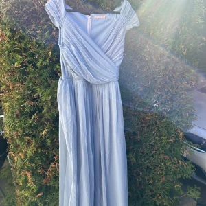 Ljusblå långklänning med omlott - Säljer en elegant ljusblå långklänning med omlott-design och korta ärmar. Perfekt för sommarens festligheter och bal 