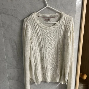 Vit stickad tröja från Iconic Sport - Säljer en stilren vit stickad tröja från Iconic Sport. Tröjan har ett snyggt flätmönster på framsidan och är tillverkad i ett mjukt material. Perfekt för kyligare dagar. Den har långa ärmar och en rund halsringning.