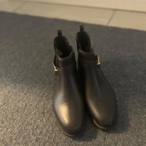 Svarta boots med spänne - Snygga svarta boots med ett dekorativt spänne på sidan. Perfekta för en stilren look och passar till många olika outfits. De har en klassisk design med rund tå och är lätta att ta på och av.