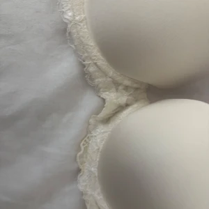 Vit vadderad bh💕 - Säljer en elegant vit bh med spetsdetaljer. Den har en slät yta och mycket  vadderade kupor. Älskar denna, men tyvärr för liten! Den är även väldigt push up! Storlek 75A/75B den är aldrig använd! 