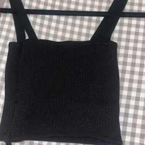 Svart ribbad croppad linnetopp med knytband -  svart ribbad croppad linnetopp med axelband och långa knytband som kan lindas runt midjan. Stretchig