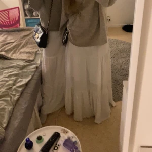 Vit lång kjol - Säljer en romantisk vit lång kjol i  storlek S (36-38). Kjolen har flera volanger och en luftig, flowy passform. Perfekt för sommarens alla tillfällen. Resår i midjan för extra komfort. De finns ett litet streck som visas men syns knappt när man har på sig den!!