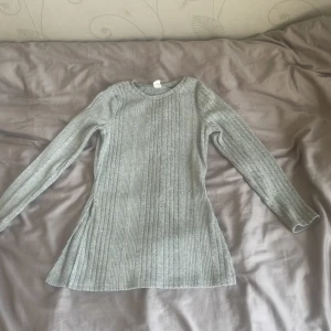 Ljusgrå ribbad stickad tröja och Ljusgrå ribbad flared byxor, set  - Säljer en ljusgrå ribbad stickad set med lång ärm och rund halsringning. Tröjan har en figurnära passform och är mjuk och stretchig, perfekt för kyligare dagar. Och byxorna är flared 